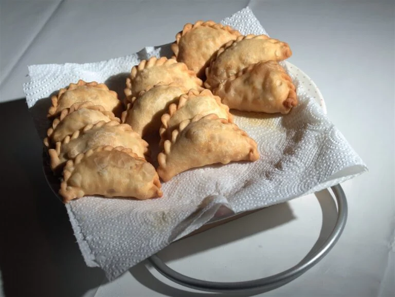 A golden, crescent-shaped Malaysian karipap pastry on a plate